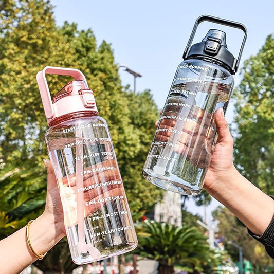 Two hands holding transparent water bottles with text designs against a blurred outdoor background.