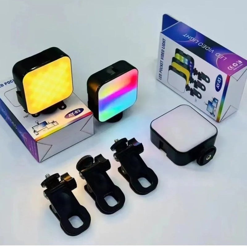 A 3-in-1 LED pocket bike light set displayed with its packaging and accessories on a light gray background. The set includes a square light with a yellow light, a square light with a rainbow light, a rectangular light with a white panel, three black mounting clips, and two product boxes.