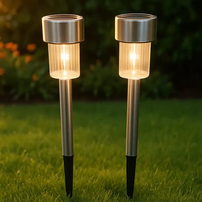 Two solar garden lights on grass with a blurred natural background