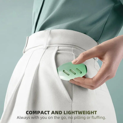 Hand holding a green fabric shaver against white pants with text 'Compact and Lightweight' on a light gray background.